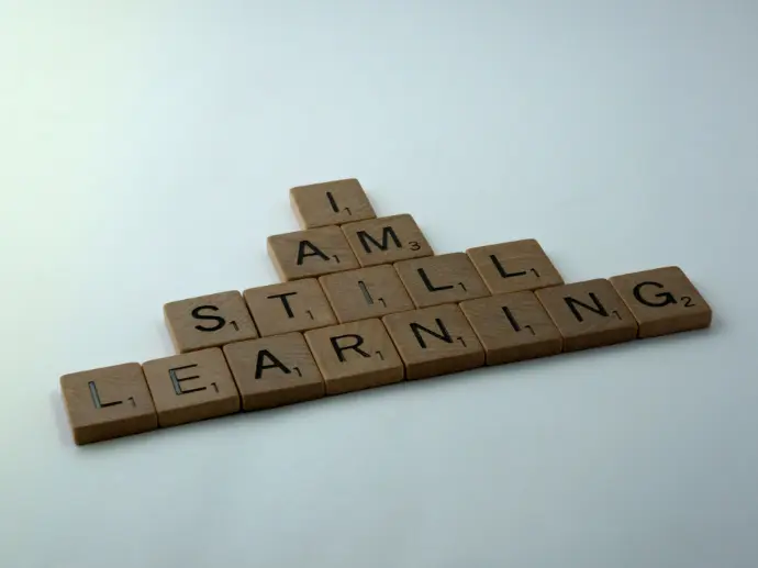 wooden scrabble letters show the words 'I am still learning'