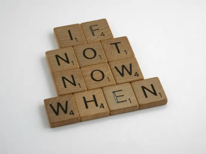 wooden scrabble letters show the words 'if not now when'